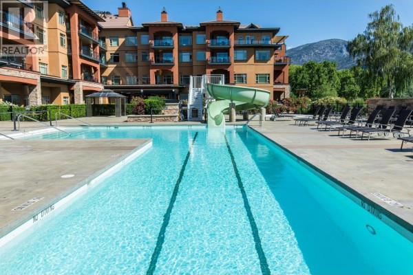Swimming pool with water slide and lounge chairs nearby. - 304-15 Park Place, Osoyoos