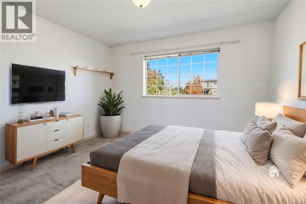 Bedroom with a bed, dresser, television, plant, and window with a view of houses. - 304 266 Hirst Ave, Parksville