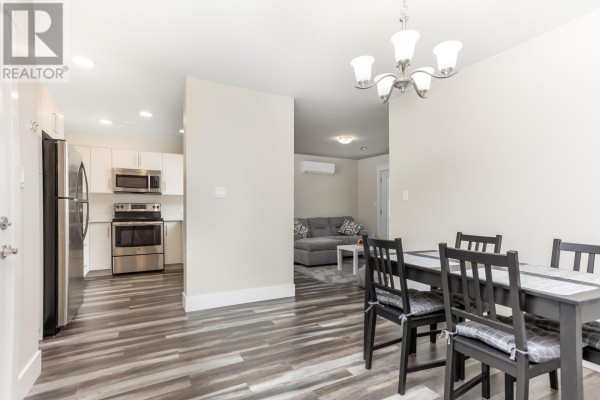 Dining area with dark wood table and chairs, opening to kitchen and living room. - 304 29 Stratford Road, Stratford