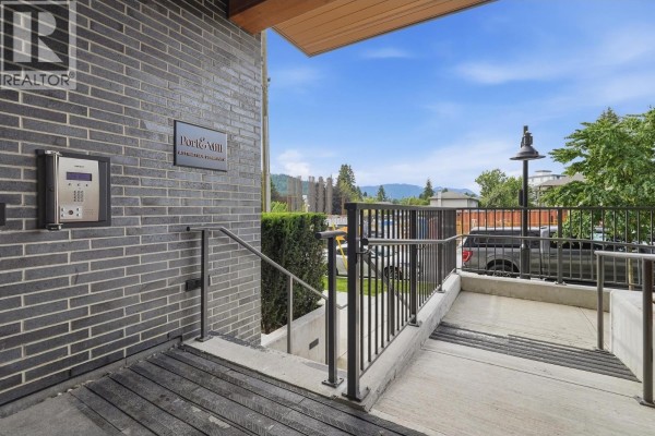 Close-up of the intercom system on a dark grey brick wall by the building entrance. - 304 648 Lea Avenue, Coquitlam