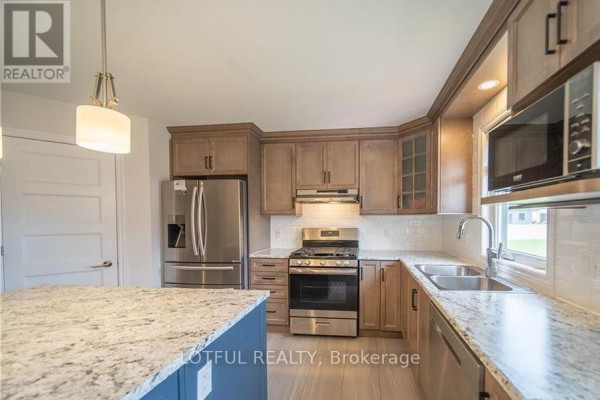 Kitchen with stainless steel appliances, light wood cabinets, granite countertops, and a central island. - 304 Belfort Street, Russell