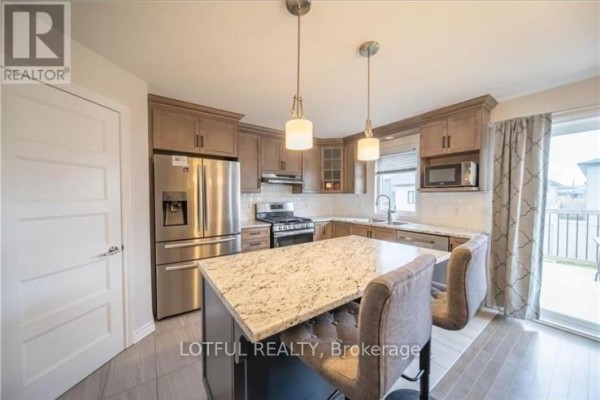 Kitchen view with a central island featuring two pendant lights, wood cabinets, and a sliding glass door. - 304 Belfort Street, Russell