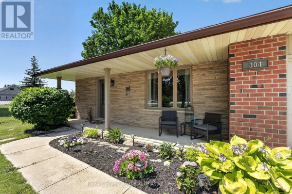 Close-up of the covered front porch with stone facade, flower beds, and two chairs. - 304 Eliza Street, Wellington North