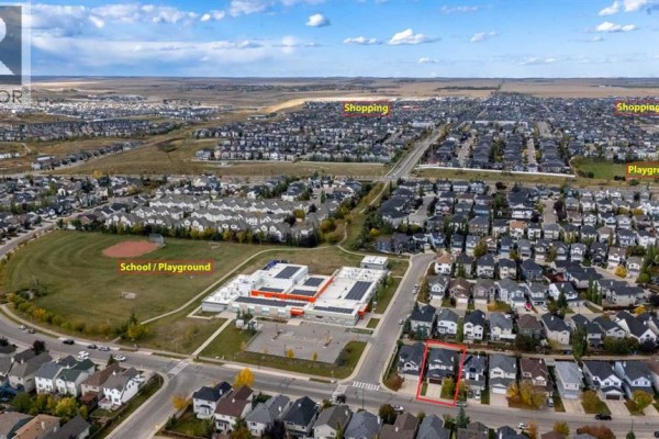 Aerial view of a suburban neighborhood showing homes, a school, playground, and shopping areas. - 304 Evanston View Nw, Calgary