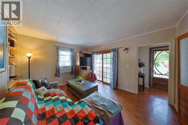 Living room with hardwood floors, patterned sofa, coffee table, and a view into the entryway. - 304 Lorne Avenue, Wallaceburg