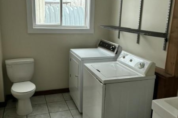 Laundry room with toilet, washing machine, dryer, and window. - 304 Mctavish Street, Outlook