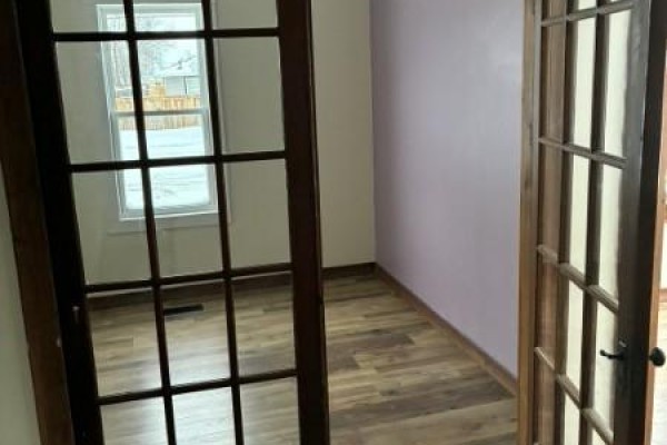 Room with purple wall, wood floor, and glass-paned doors leading outside. - 304 Mctavish Street, Outlook