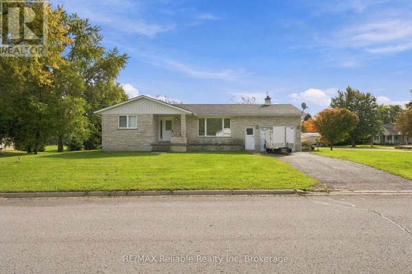 Street view of a single-story house with a manicured lawn and mature trees. - 304 Morris Street, North Huron
