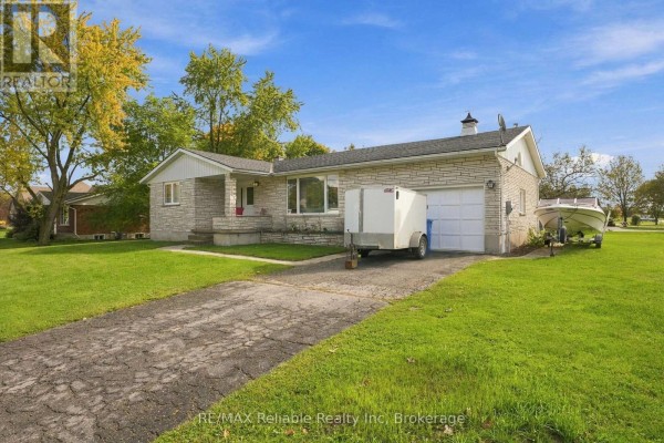 Side view of a brick house with a driveway, garage, and boat trailer. - 304 Morris Street, North Huron