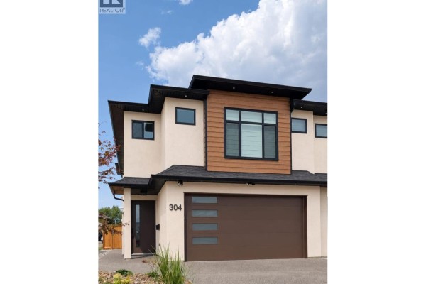 Open concept living area with a modern kitchen, island, and fireplace. - 304 Sumac Road Unit# 1, Kelowna
