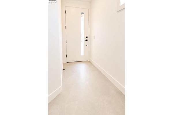 Kitchen with white cabinets, stainless steel appliances, and a large island. - 304 Sumac Road Unit# 1, Kelowna