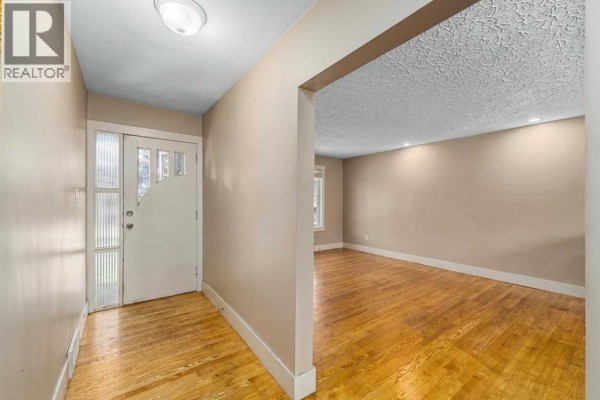 Entranceway with a white door featuring frosted glass panels and hardwood floors. - 3042 28 Street Sw, Calgary