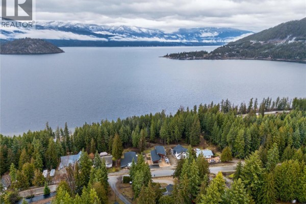 Aerial view of houses nestled among trees overlooking a large lake with mountains in background. - 3044 Cedar Drive, Blind Bay