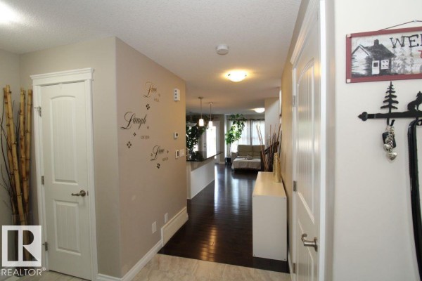 Hallway entrance with white doors, dark wood floors, and decorative wall decals. - 3048 Harvey Cr Nw, Edmonton