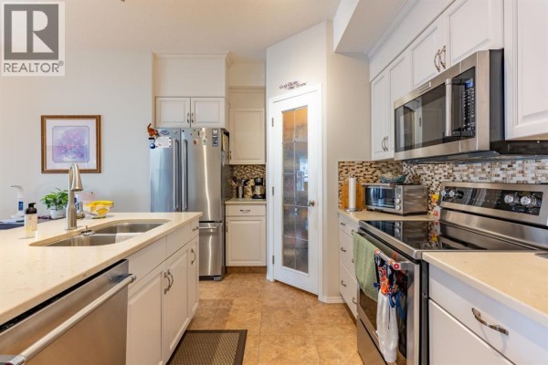 Kitchen with white cabinets, stainless steel appliances, and tiled backsplash. - 305, 29 River Ridge Drive Nw, Medicine Hat