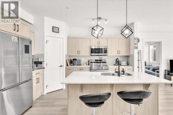 Modern kitchen with a large island, stainless steel appliances, and light wood cabinetry. - 305, 30 Sage Hill  Nw, Calgary