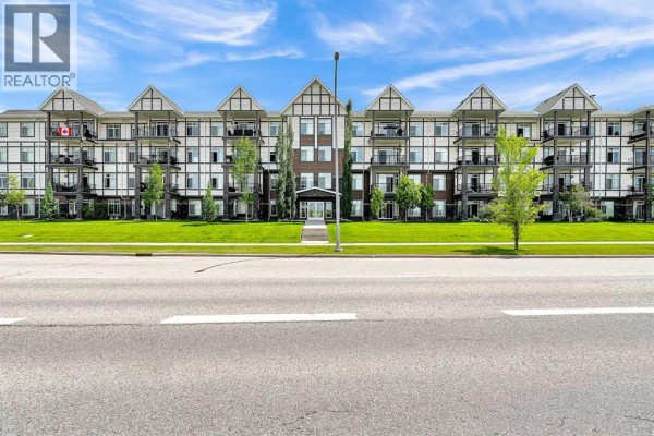 Exterior view of apartment building with manicured lawn and street. - 305, 6703 New Brighton Avenue Se, Calgary