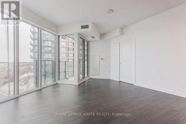 Spacious room with dark hardwood floors, floor-to-ceiling windows, and a sliding glass door to a balcony. - 305 - 100 Eagle Rock Way, Vaughan
