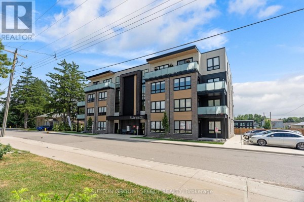 Open-concept living area with light wood floors, a modern kitchen island, and stainless steel appliances. - 305 - 15 James Street, South Huron