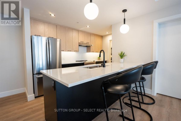 Close-up of a kitchen island with black stools, quartz countertop, and a black faucet. - 305 - 15 James Street, South Huron