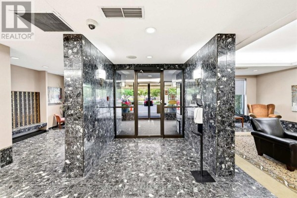 Building lobby with dark patterned marble walls and floors, glass doors, and seating areas. - 305 - 900 Wilson Road N, Oshawa