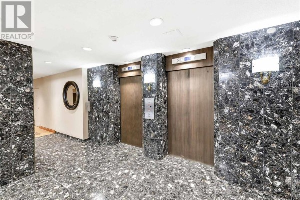Building lobby with dark patterned marble walls and floors, and two wood-paneled elevators. - 305 - 900 Wilson Road N, Oshawa