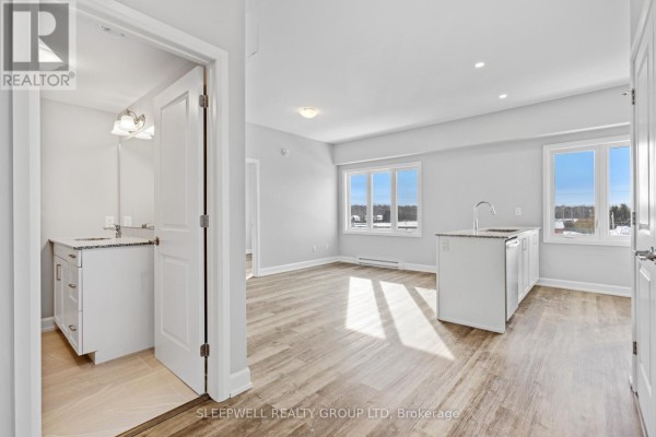 Kitchen with white cabinetry, stainless steel appliances, and an island next to a living area. - 305 - 979 North Russell Road, Russell