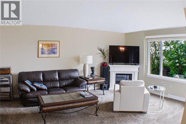 Communal lounge with a large curved wicker sofa, chairs, and a long dining table. - 305 103 Gorge Rd E, Victoria