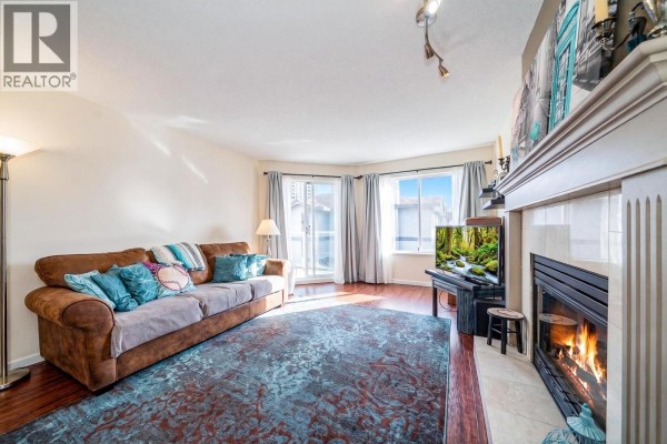Living room with a sofa, fireplace, and view of a balcony. - 305 1167 Pipeline Road, Coquitlam
