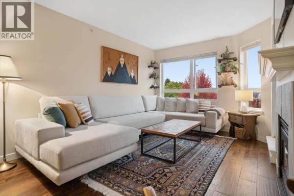 Living area and kitchen with hardwood floors, a sectional sofa, and a dining area. - 305 1707 Charles Street, Vancouver