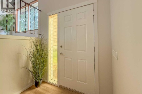 Side exterior of a beige bi-level house with large windows and gravel landscaping. - 305 51 Avenue, Coalhurst