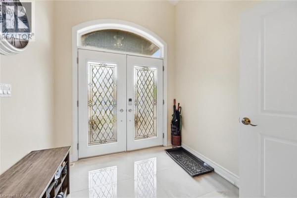 Interior foyer with double glass doors, tiled floor, and shoe storage bench. - 305 Caledon Avenue, Hamilton