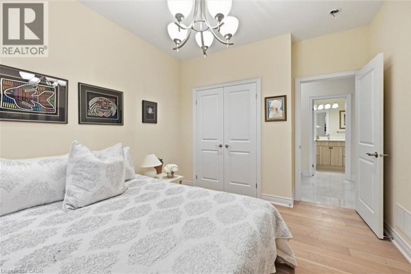 Bedroom with a bed, closet doors, and an adjoining bathroom entrance. - 305 Caledon Avenue, Hamilton