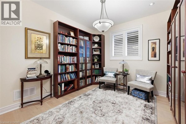 Home office with built-in mahogany bookshelves, two chairs, and a large area rug. - 305 Caledon Avenue, Hamilton