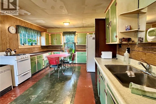 Vintage kitchen with green cabinets, diner table, wood panel walls, and white stove - 305 North Cayuga Street W Dunnville