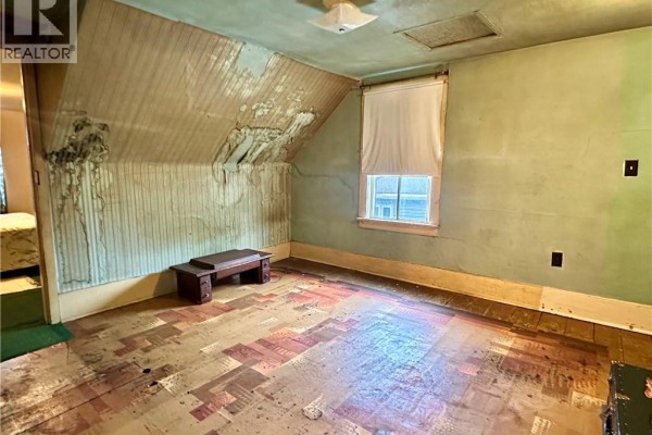Sloped ceiling bedroom with peeling wallpaper and worn flooring - 305 North Cayuga Street W Dunnville