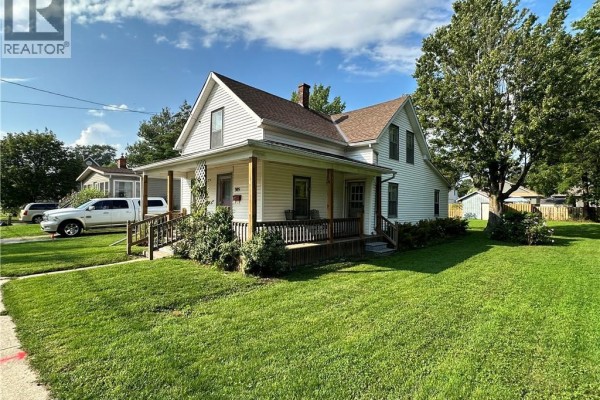 Right side view of white house with porch, green lawn, and mature trees. - 305 North Cayuga Street W, Dunnville