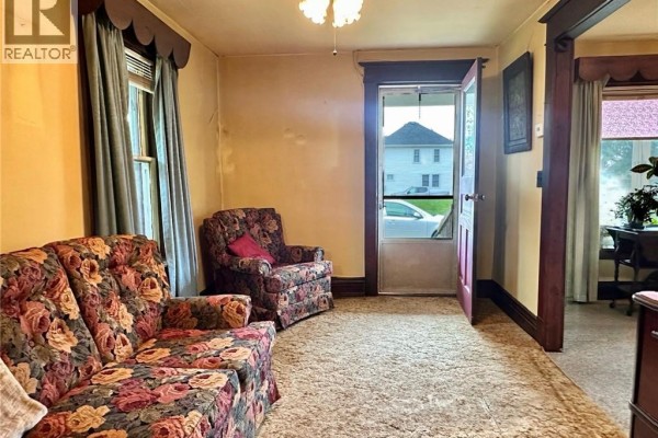 Floral sofa & armchair in living room with screen door - 305 North Cayuga Street W Dunnville