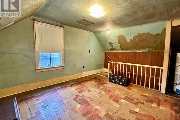 Attic room with sloping ceiling, window, wood paneling, and vintage suitcase - 305 North Cayuga Street W Haldimand