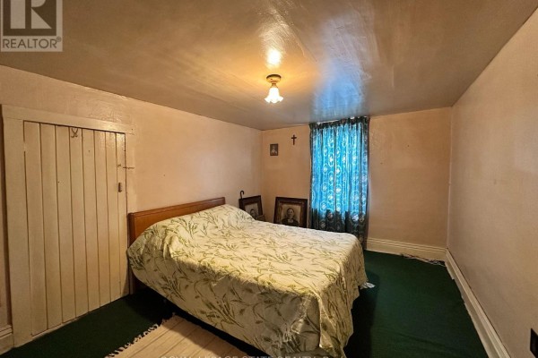 Bedroom with bed, patterned comforter, wooden closet door, blue curtains - 305 North Cayuga Street W Haldimand