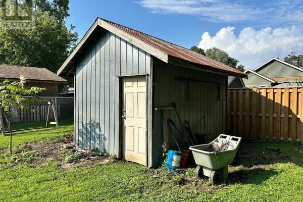 Green shed with garden tools, wheelbarrow, and fence - 305 North Cayuga Street W Haldimand