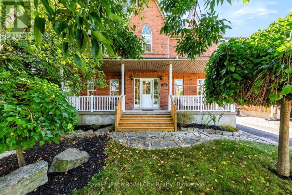 Front view of a brick house with a covered porch, wooden steps, and stone pathway. - 305 Ridge Road, Guelph/eramosa