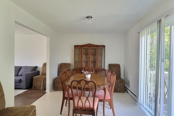 Living room with a grey sectional sofa, white armchair, television, and a bay window. - 305 Rue Des Forages, Gatineau