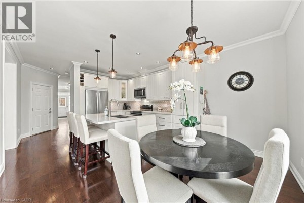 Open concept kitchen and dining area with white cabinets, stainless steel appliances, and dark wood floors. - 3053 Jenn Avenue, Burlington