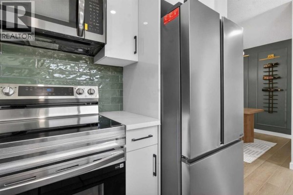 Kitchen featuring double sink, window, and wooden cabinetry - 306, 5340 17 Avenue Sw, Calgary