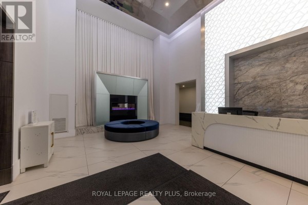 Apartment lobby features a modern fireplace, textured wall, and a white front desk. - 306 - 16 Concord Place, Grimsby
