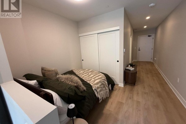 Bedroom with sliding closet doors and a view down a hallway towards the apartment entrance. - 306 - 275 Carling Avenue, Ottawa