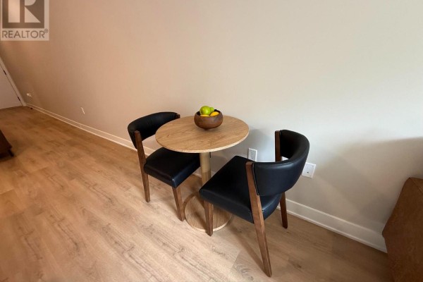 Small dining area with a round wooden table and two black chairs. - 306 - 275 Carling Avenue, Ottawa