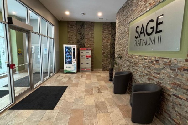Building lobby with stone accent wall, vending machines, mailboxes, and two modern chairs. - 306 - 308 Lester Street, Waterloo