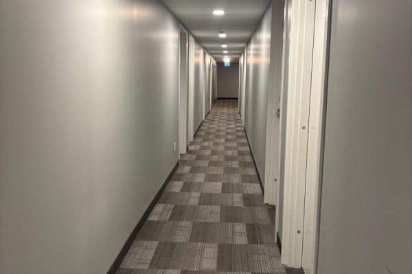 Long, well-lit apartment building hallway with grey walls and a patterned carpet. - 306 - 308 Lester Street, Waterloo